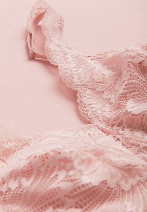 Zarter rosa Spitzen-BH mit floralen Mustern und verstellbarem Träger, auf einem weichen rosa Stoffhintergrund gelegt.