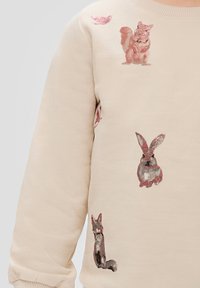 Beige sweatshirt met illustraties van een eekhoorn, konijn en vos, met metallic accenten en een zachte textuur.