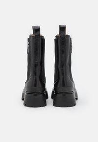 Mustat nilkkurit, joissa on tyylikäs nahkapinta, sivuissa joustavat paneelit ja paksut kumipohjat. Varustettu repimisnauhoilla ja minimalistisilla muotoiluelementeillä.