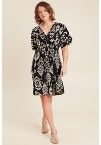 Schwarzes Kleid mit weißen geometrischen Mustern, kurzen Ärmeln, V-Ausschnitt und geraffter Taille; leichtes Material mit fließender Silhouette.