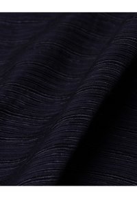 Mörk marinblått tyg med ett texturerat, vågigt mönster. Har fina, horisontella linjer som skapar en subtil djupkänsla. Mjukt och slätt avslut.