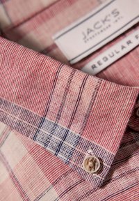 Rood en blauw geblokt shirtstof met een gestructureerde weving. Bevat een knoop en een label met de tekst "JACK'S REGULAR FIT."