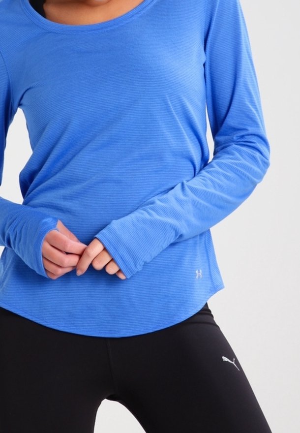 Pitkähihaista urheilu-paitaa kirkkaan sinisenä, verkkokudoksella, pyöreällä kaula-aukolla ja peukalonrei'illä. Yhdistetty mustiin leggings-pantalonkeihin.