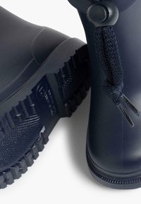 Bottes en caoutchouc bleu marine avec une semelle extérieure texturée, dotées d'un détail de lacets tissés, d'une surface lisse et d'un design à bout rond.