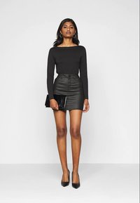 Black long-sleeve top, high-waisted black leather mini skirt, sleek black clutch, and black high heels; smooth textures and fitted design.