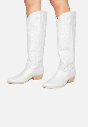 Stivali da cowboy bianchi al ginocchio con punta appuntita, caratterizzati da motivi a spirale in rilievo, tacco basso impilato e una texture in pelle liscia.