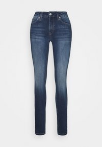Jeans ajustados de mezclilla azul oscuro, con una cintura alta, diseño de cinco bolsillos, un ligero desgaste y una textura suave.
