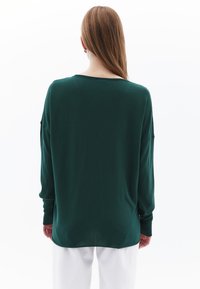 Grüner, langärmeliger Pullover mit lockerer Passform, gerippten Bündchen und weitem Ausschnitt, aus einem weichen, strukturierten Stoff gefertigt.