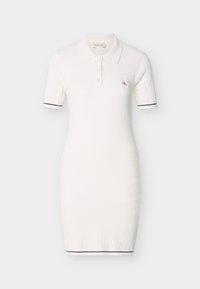 Λευκό πλεκτό φόρεμα πόλο με κοντά μανίκια, που διαθέτει γιακά και μικρό λογότυπο. Διακοσμημένο με ναυτικά ρίγες στα τελειώματα των μανικιών.