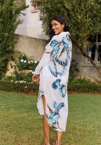 Witte doorschijnende kimono met een blauw bloemenprint, lange mouwen en zijsplitten. Het lichte weefsel valt losjes om het lichaam.