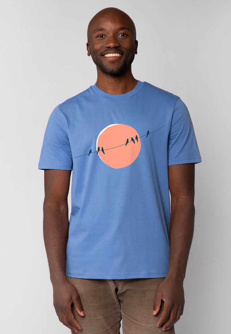 Lichtblauw T-shirt van katoen, voorzien van een grote oranje zonafbeelding met donkere groene vogels op een draad die over de borst zijn bedrukt.