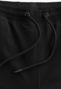 Sorte shorts med elastisk talje og snor, der har en glat overflade og forstærket syning.