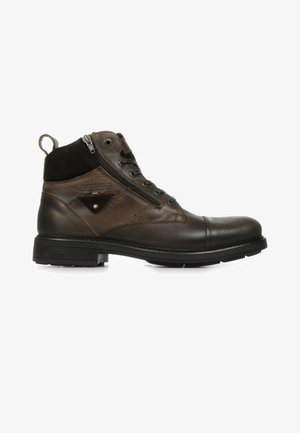 Bottines en cuir marron avec une tige en daim, dotées d'une fermeture éclair sur le côté, de lacets et d'une semelle texturée pour l'adhérence. Logo Redskins visible.