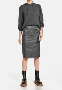 Šedá mikina s kapucí a šňůrkami je v kombinaci se šedou džínsovou tužkovou sukní. Černé chunky-heeled kotníkové boty dodávají outfitu závěrečný dotek. Celý outfit má hladkou strukturu.