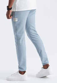 Vaaleansinisiä collegehousuja, jotka on valmistettu teksturoituneesta kankaasta. Niissä on slim fit -leikkaus, joustavat hihnat ja etiketti takataskussa. Tyylitetty valkoisilla lenkkarilla.