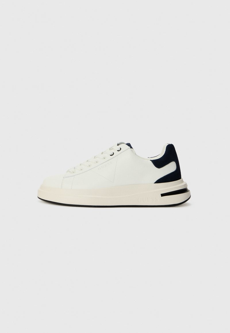 Hvite lave sneakers med marineblå detaljer, teksturert overflate, flate lisser, tykk såle og preget logo på siden.