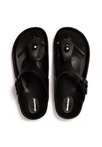 Sandalias negras con superficie texturizada, diseño de tiras y hebilla ajustable. Fabricadas con material duradero, presentan un gran acento circular.
