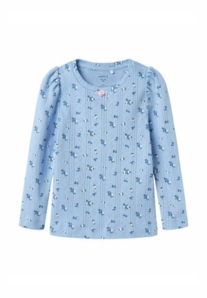 Chemise pour bébé à manches longues de couleur bleu clair, ornée de petits motifs floraux blancs et bleus, avec une décoration en forme de rose rose près de l'encolure.