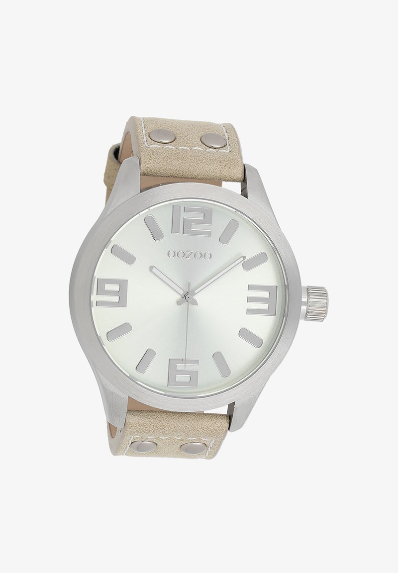 Montre en métal argenté avec un cadran rond, bracelet en cuir beige, grands chiffres arabes et un design minimaliste avec des accents métalliques.