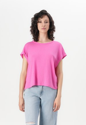 Fuchsia kortermet topp med rund hals og rullede ermene, paret med lyseblå denimjeans med slitt kant.