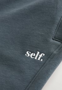 Donkergrijs katoenen sweatshirt met een geborduurde "self." logo in het wit. Glad textuur met een relaxte pasvorm en zichtbare stikseldetails.