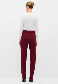 Bordeaux op maat gemaakte broeken met een gladde textuur, hoge taille en een achterzak, gecombineerd met een aansluitend wit t-shirt met lange mouwen.