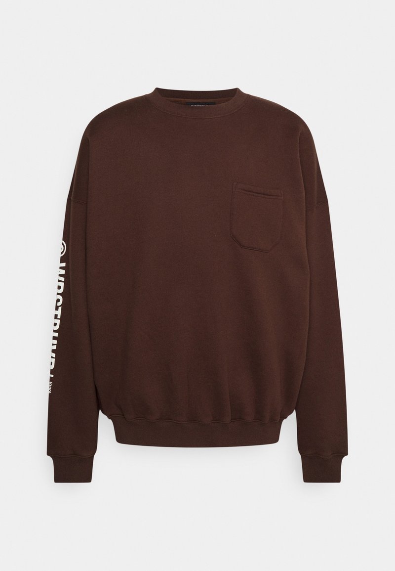 Sweat-shirt marron à manches longues avec col rond, poche poitrine avant et texte blanc partiellement visible sur la manche gauche.