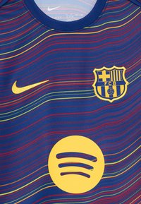 FC Barcelona jersey, blue with multicolor wavy stripes. Features yellow Nike logo, team crest, and large yellow Spotify logo. Smooth fabric.