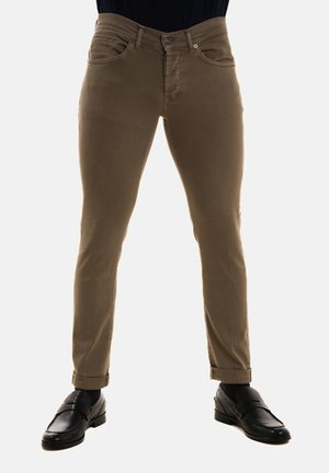 Pantaloni slim-fit marroni con una texture liscia, dotati di tasche anteriori, passanti per cintura e chiusura con bottone. Abbinati a scarpe eleganti nere.