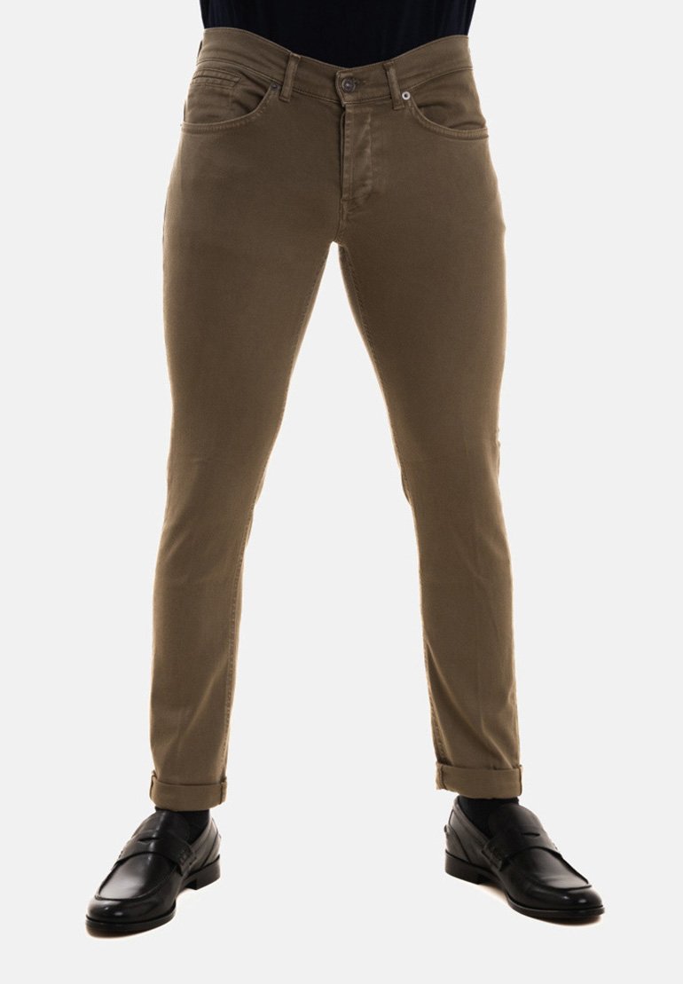 Pantaloni slim-fit marroni con una texture liscia, dotati di tasche anteriori, passanti per cintura e chiusura con bottone. Abbinati a scarpe eleganti nere.