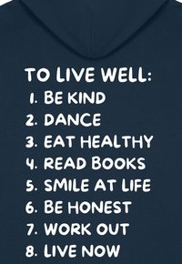 Hanoracul de marină are un text mare alb care lista opt sfaturi pentru bunăstare, inclusiv "Fii bun" și "Dansează", cu un design simplu și îndrăzneț al fontului.