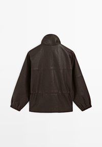 Brun läderjacka med hög krage, elastiska ärmslut och samlad midja. Har texturerat material och subtil sömdetaljering.