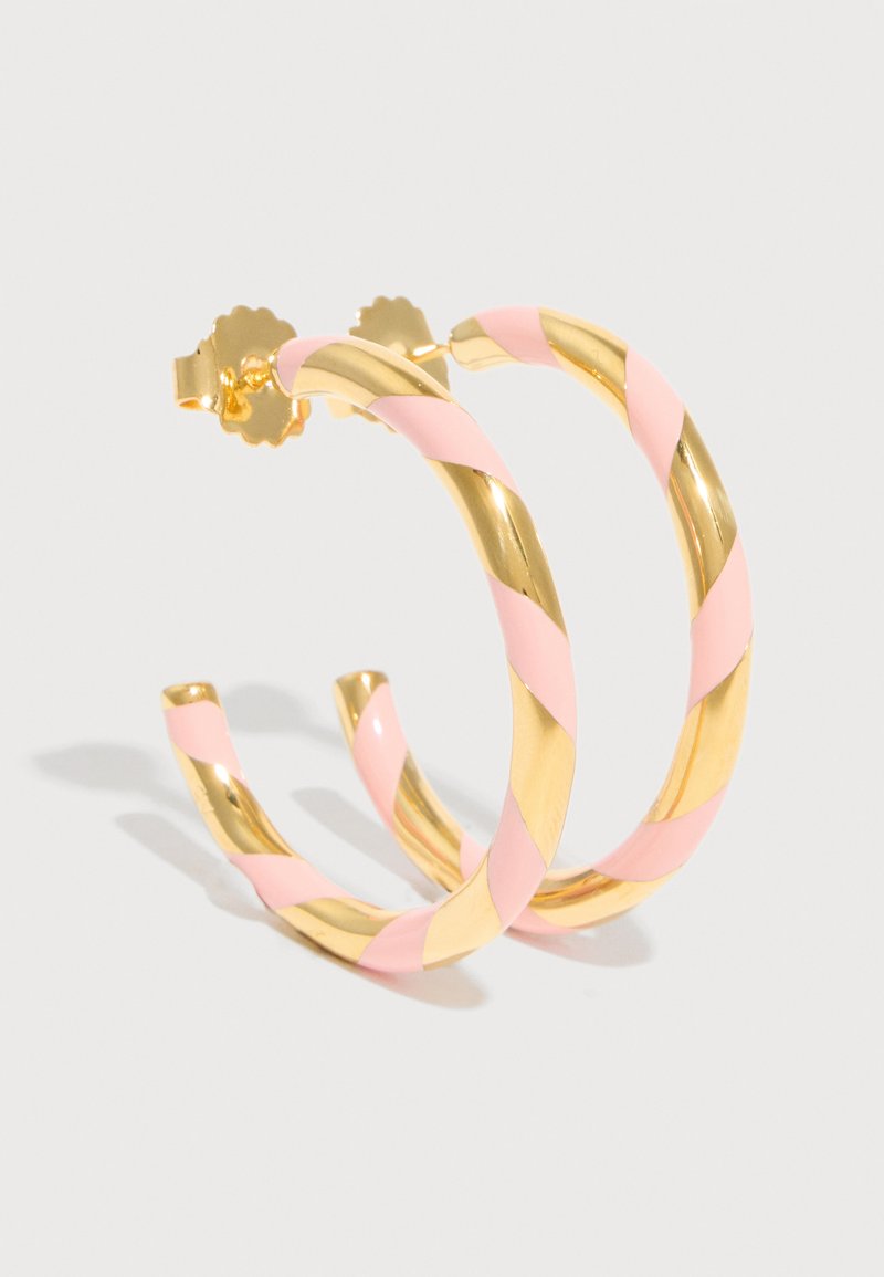 Złote kolczyki koła skręcone z pastelowymi różowymi emaliowanymi paskami, przedstawione na białym tle z zapięciami motylkowymi.