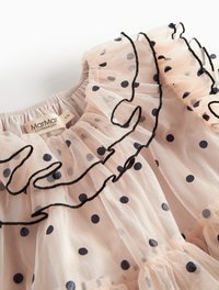 Kerge roosa tülli kleit, millel on tumepruunid konnnupud. Omab volangiga kaelust ja musta äärt. Elastne vöökoht ja voolav kihiline disain.