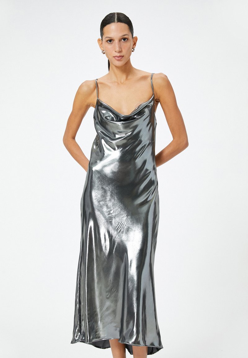 Metallisch silbernes Slipkleid mit cowl-Ausschnitt und dünnen Trägern, das eine glatte, reflektierende Textur und eine fließende Silhouette bis zur Midi-Länge aufweist.