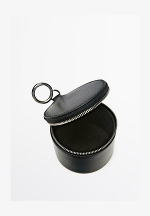 Custodia rotonda nera in pelle con zip e portachiavi, aperta per mostrare l'interno vuoto su sfondo bianco.