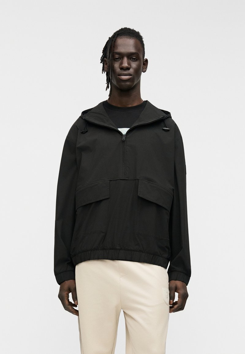 Μαύρο φούτερ με κουκούλα, με δύο τσέπες στο μπροστινό μέρος, φερμουάρ στο λαιμό και ελαστική μέση. Λείο, ελαφρύ ύφασμα.