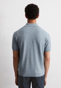 Jasnoniebieska koszulka polo z krótkim rękawem o teksturowanym splocie, z prążkowanym kołnierzykiem i prostym dołem, bez widocznych logotypów lub wzorów.