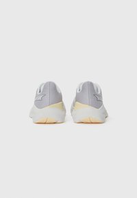 Gray athletic shoes with a smooth fabric upper, contrasting yellow heel accents, and a textured rubber sole.