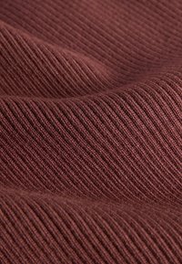 Close-up of soft, ribbed knit fabric in a warm brown color with textured, parallel ridges and gentle folds.