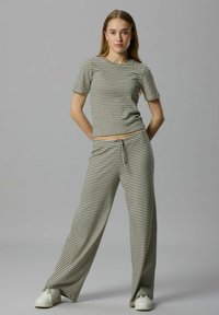 Ensemble de vêtements d'intérieur en tricot rayé composé d'un haut ajusté à manches courtes et de pantalons à jambe large, dans des tons neutres avec une taille élastique à cordon.