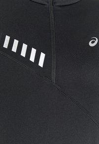 Schwarzes Sportoberteil aus elastischem Material mit einem Reißverschluss, diagonaler Nahtdesign und reflektierenden silbernen Akzenten auf der Brust.