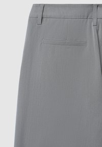 Pantaloni grigi realizzati in tessuto liscio, con un taglio dritto, due tasche posteriori con patta e passanti per la cintura.