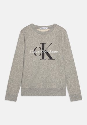 Szara bluza z długim rękawem i okrągłym dekoltem, z czarnym logo "ck" i białym logo "Calvin Klein Jeans" na środku przodu.