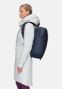 Sac à dos bleu marine au design élégant et rectangulaire, fabriqué en matériau durable, avec une poche zippée à l'avant et des bretelles rembourrées.
