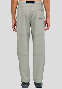 Ljusgrå utomhusbyxor med lös passform, elastisk midja och bakficka; har sydd panelering och texturerad tyg.