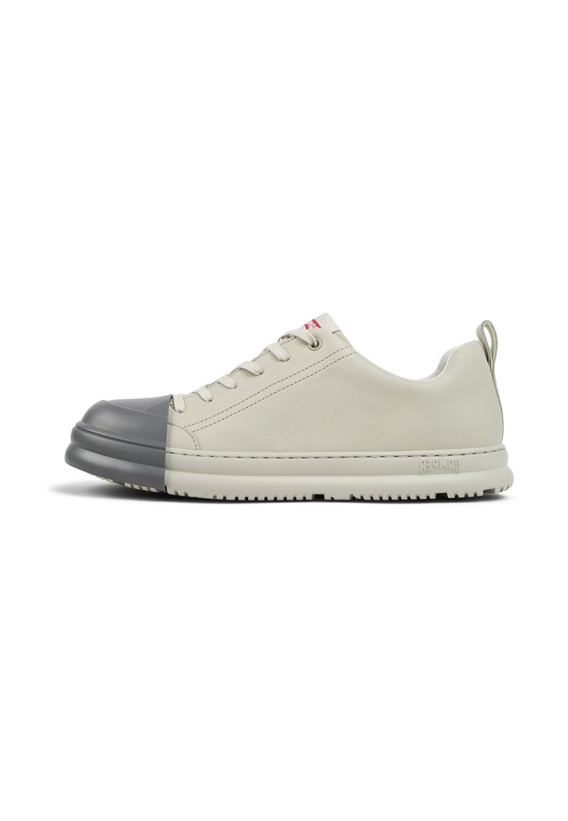 Sneaker in pelle beige con puntale in gomma grigia, lacci tondi e suola texturizzata. Disponibile con una linguetta sul retro per facilitare l'indossamento.