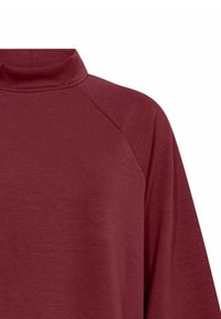 Bordo pitkähihaine paita korkealla kaula-aukolla ja raglan-hihoilla, joka paljastaa ylärinnan ja olka-alueen valkoista taustaa vasten.