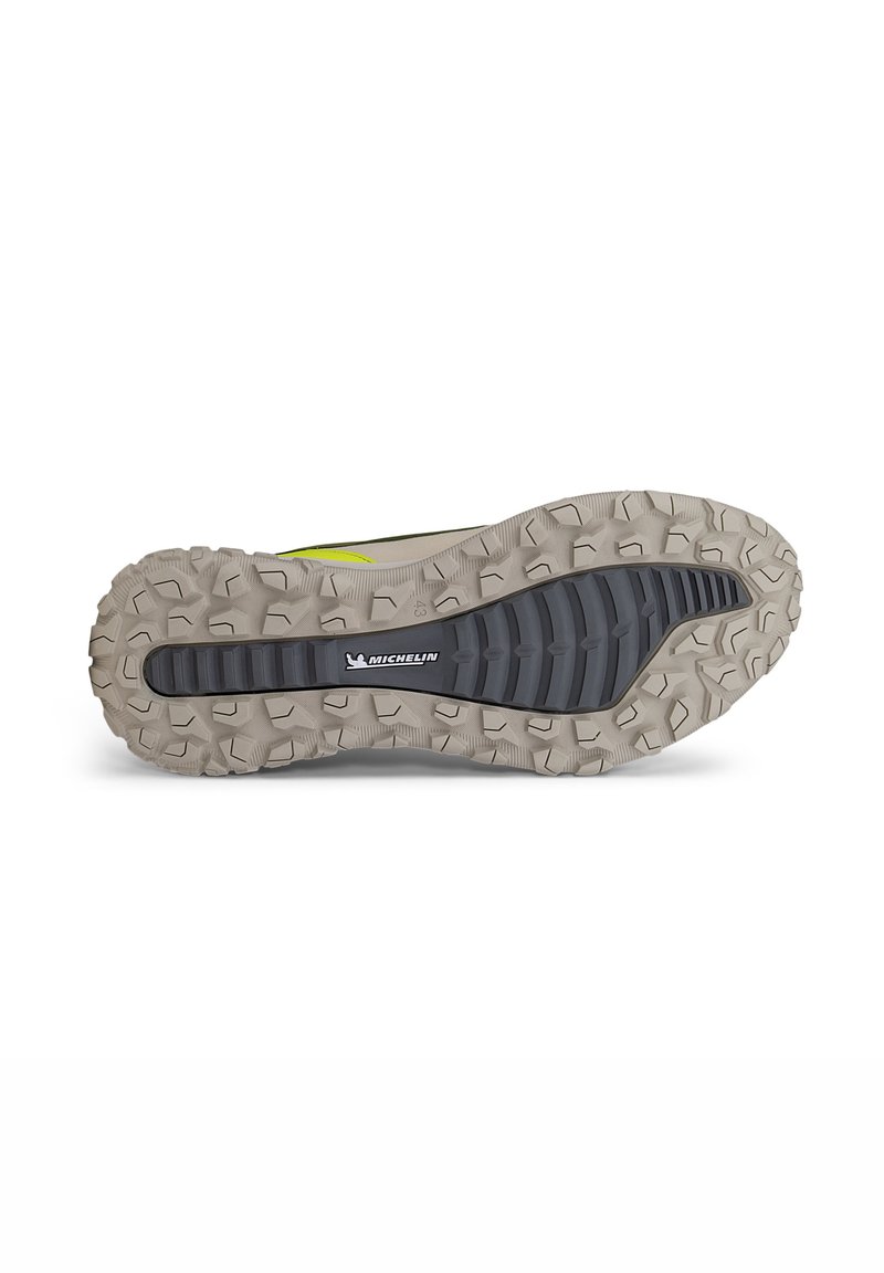 Suela de zapatilla de trail con una suela de goma que presenta tacos profundos y multidireccionales para mayor tracción. La combinación de colores incluye tonos grises, beiges y acentos en negro.