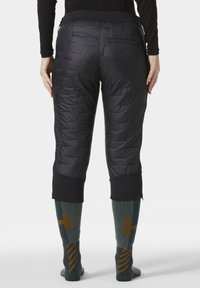 Zwarte gewatteerde capri-broeken met een textuurafwerking. Voorzien van een elastische tailleband en ritssluitingen aan de zoom. G gedragen met geprinte kniekousen.